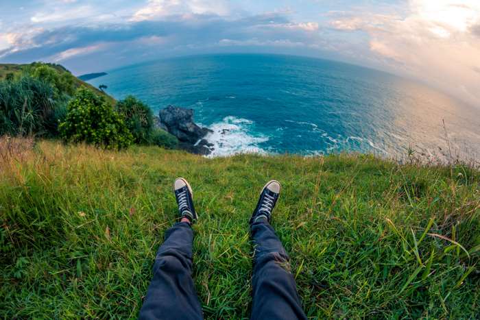 Person sitting on a grassy cliff overlooking the ocean
