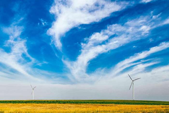 Wind turbines in a golden field under a cloudy sky