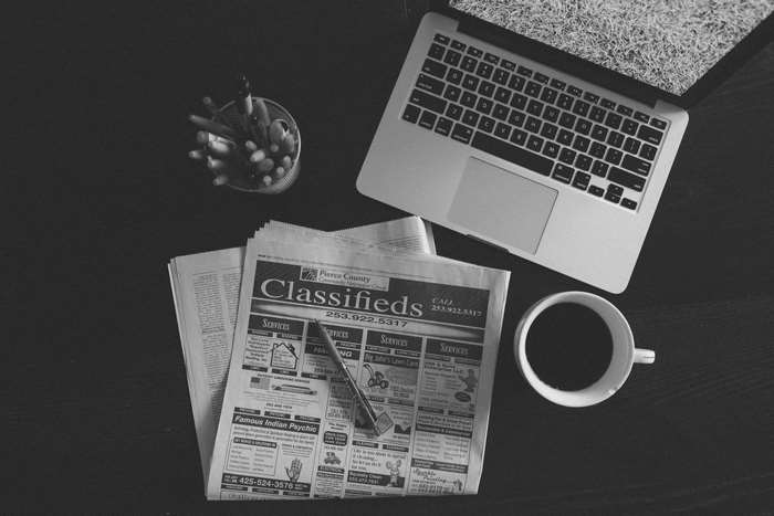 Black and white image of a laptop, newspaper, and coffee cup