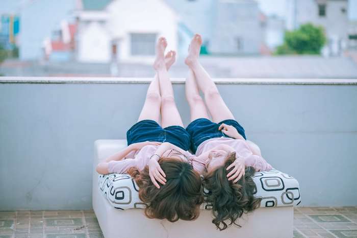 Two young women lying on a couch with legs up