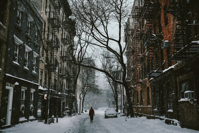 Person walking down a snowy street in a city