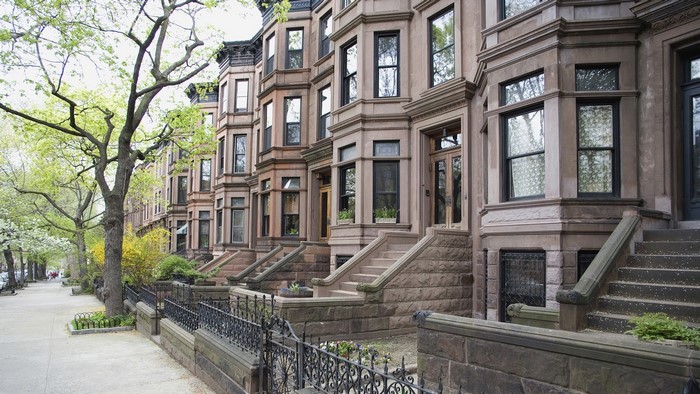 Brownstone row houses on a tree-lined street in New York