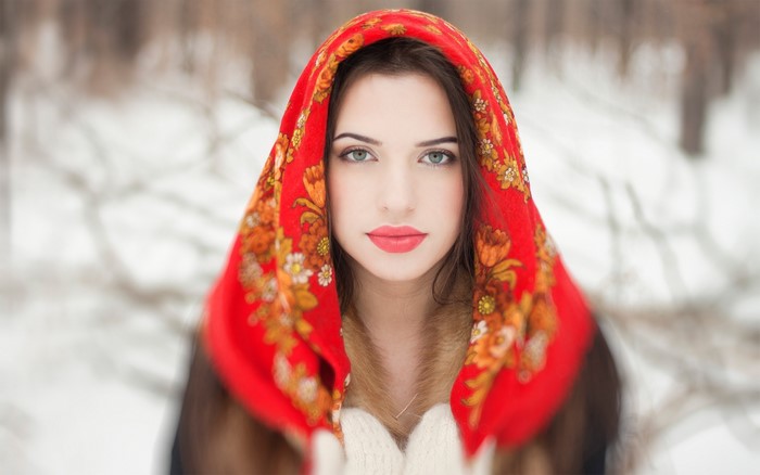Brunette girl wearing a red scarf and mittens in the snow