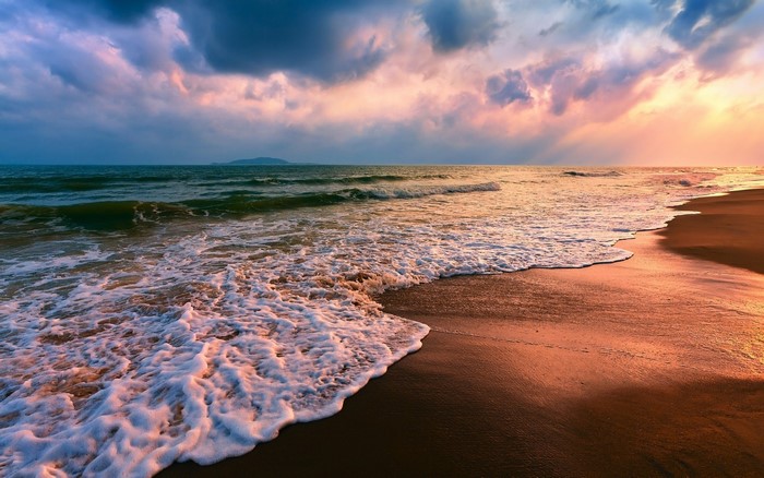 Waves crashing on a sandy beach at sunset