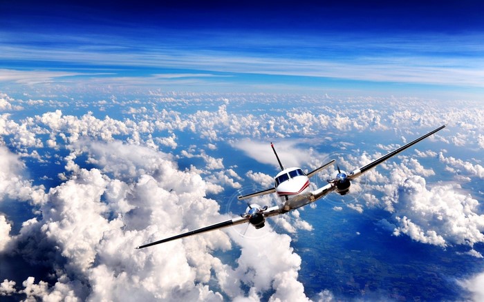 Airplane flying above clouds in the sky
