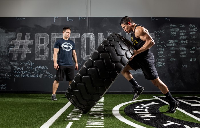 Athletes performing tire flips in a gym