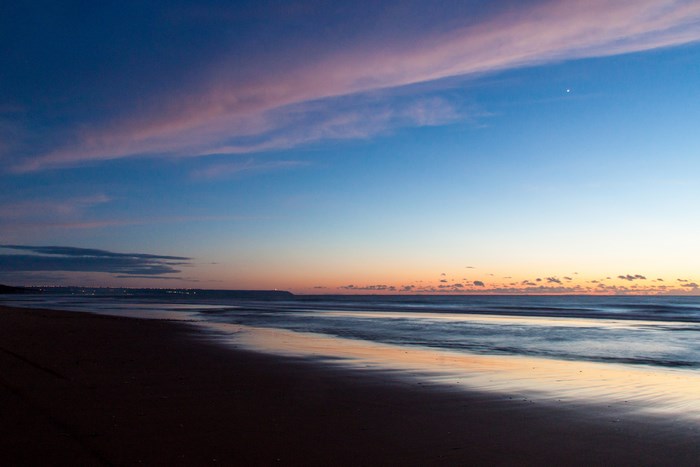 Beach at dusk with colorful sky and ocean waves