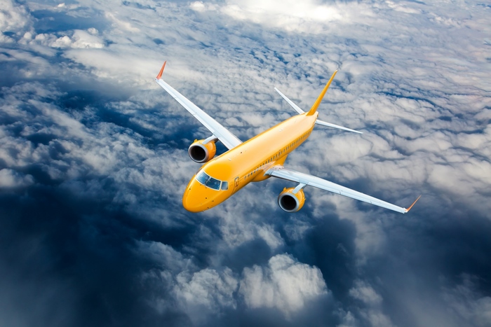 Yellow airplane flying above clouds