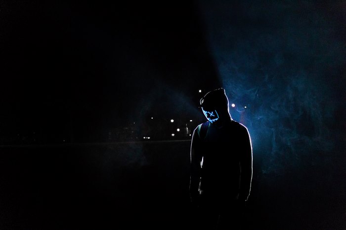 Person wearing a neon mask in the dark