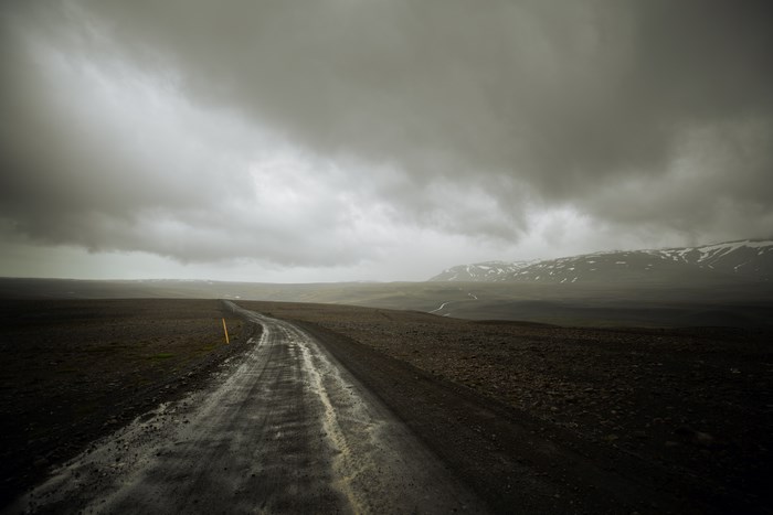 A Wet Road Through a Barren Landscape in Iceland Under Stormy Skies