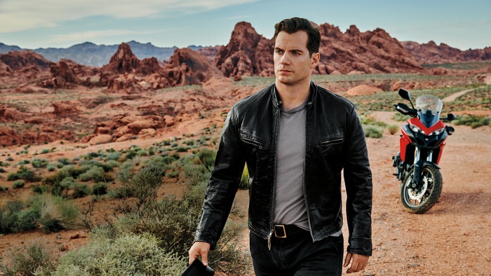 Henry Cavill in a leather jacket with a motorcycle in the desert