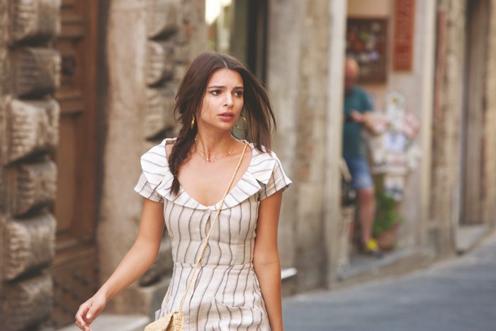 Emily Ratajkowski in a striped dress walking down a street