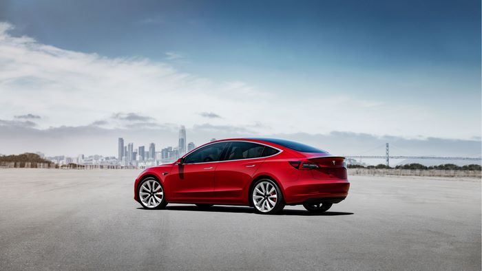 Red Tesla Model 3 in front of city skyline