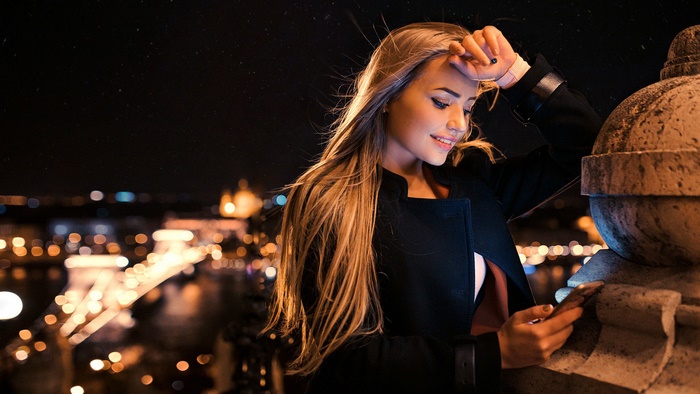Woman with long blonde hair looking at her phone at night