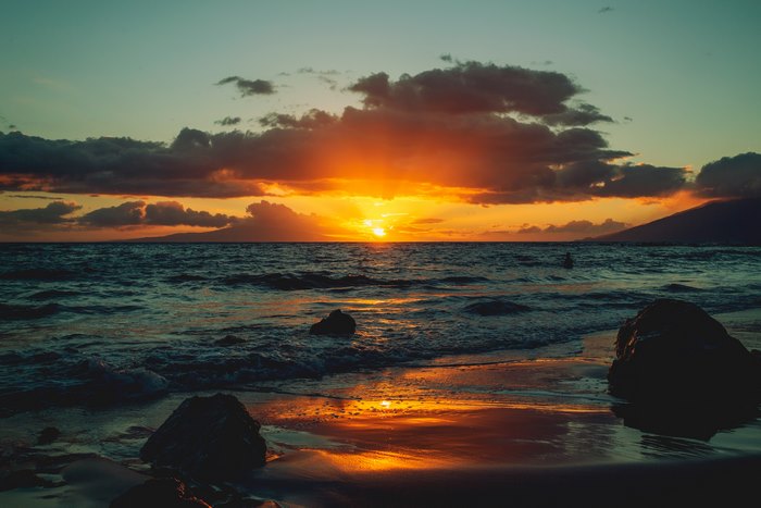 Sunset over the ocean with clouds and mountains