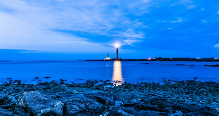 Lighthouse on the rocky shore at dusk