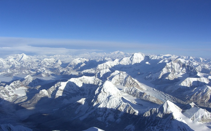 Aerial view of snow-capped Himalayan mountains under a clear blue sky