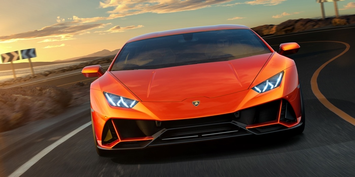 Orange Lamborghini Huracan EVO driving on a coastal road