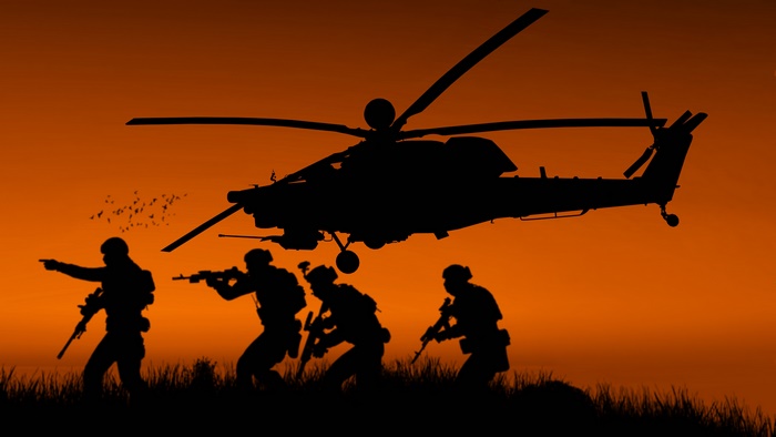 Silhouette of soldiers and military helicopter at sunset