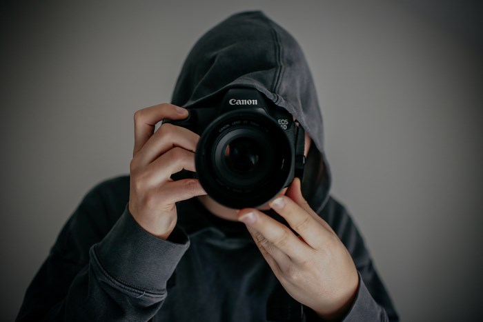 Person in hoodie holding Canon EOS 5D camera