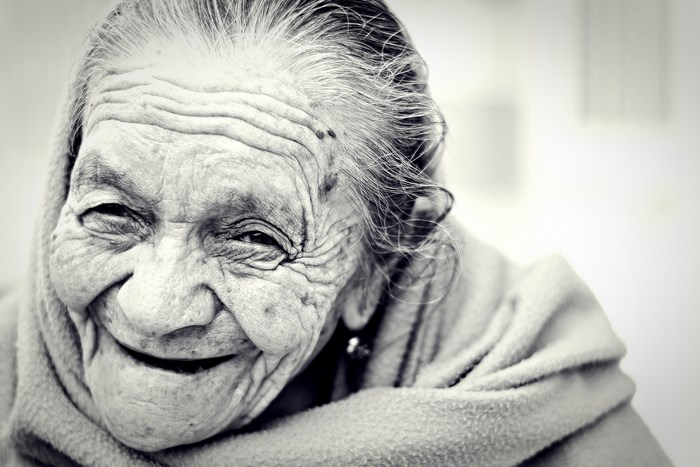 Elderly woman smiling, wrapped in a blanket