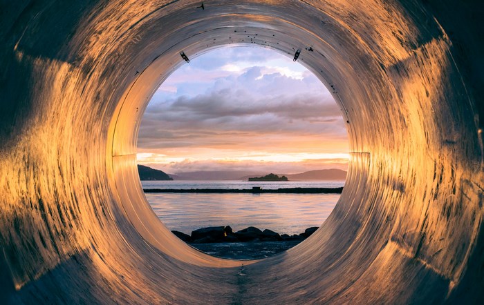 View of sunset over water through a pipe