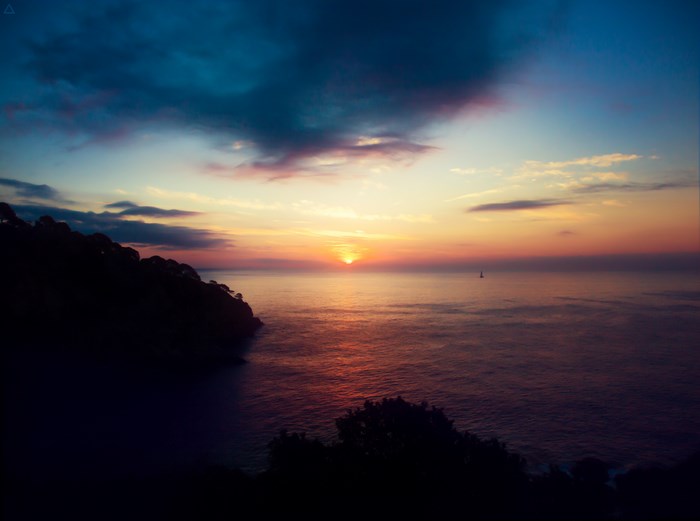 Sunset over the ocean with a sailboat