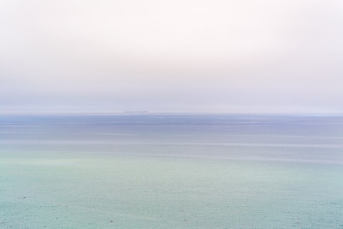 Ocean horizon with distant land and cloudy sky
