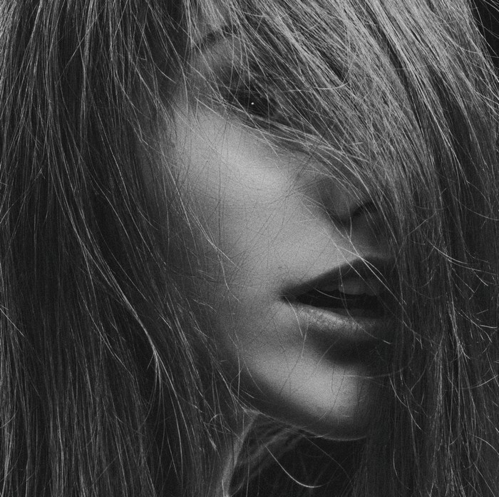 Monochrome close-up of a woman's face with hair obscuring her features