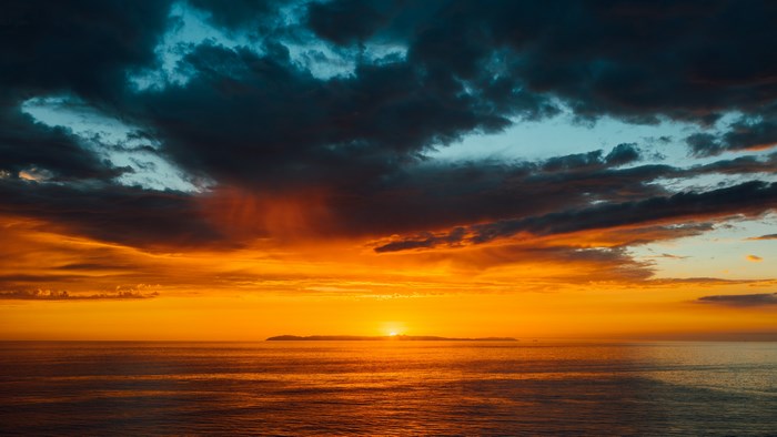 Sunset over the ocean with island and clouds