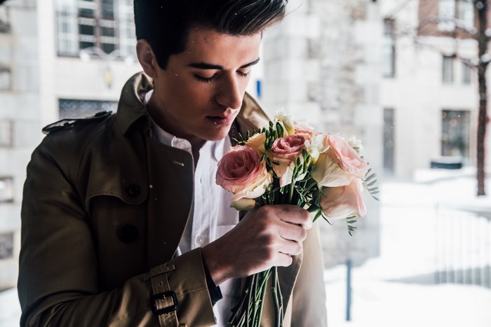 Man in trench coat holding a bouquet of roses