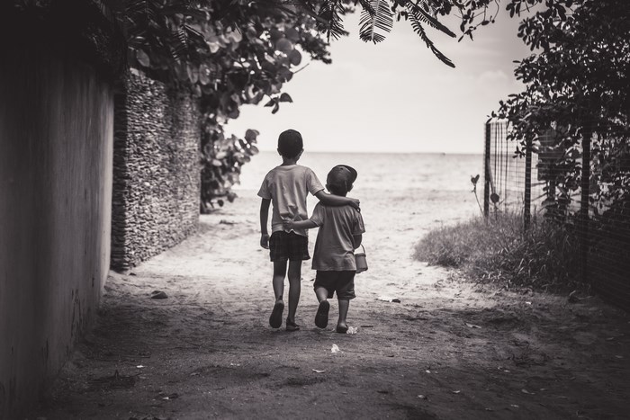 Two young brothers walking on a beach path