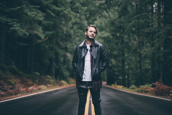 Man in leather jacket standing on a forest road