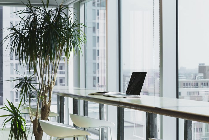 Laptop on a counter with a plant and city view