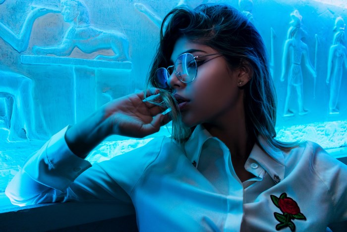 Woman with glasses and rose patch shirt in blue light