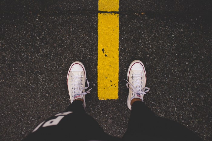 Person standing on asphalt road with yellow line