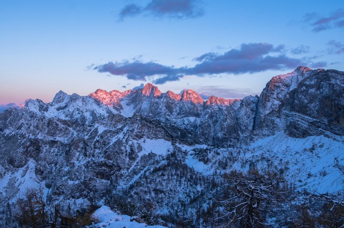 Snowy mountain range at sunrise with pink clouds