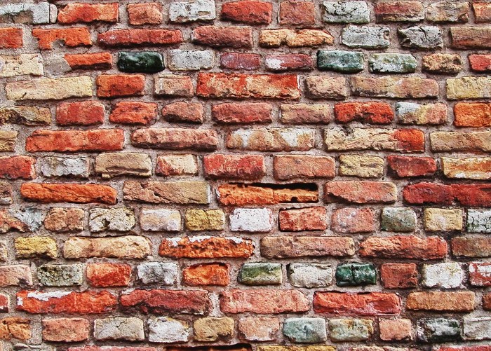 A textured wall of weathered red and white bricks