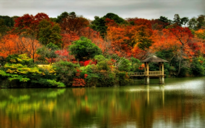 Autumn foliage reflected in a tranquil lake with a gazebo