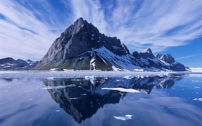 Snow-capped mountain reflected in icy water