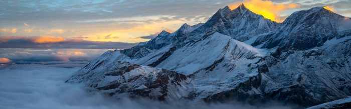 Snowy mountain peaks at sunrise above clouds