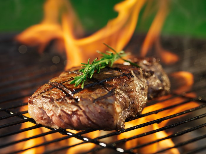 Grilled Steak with Flames and Herb Garnish