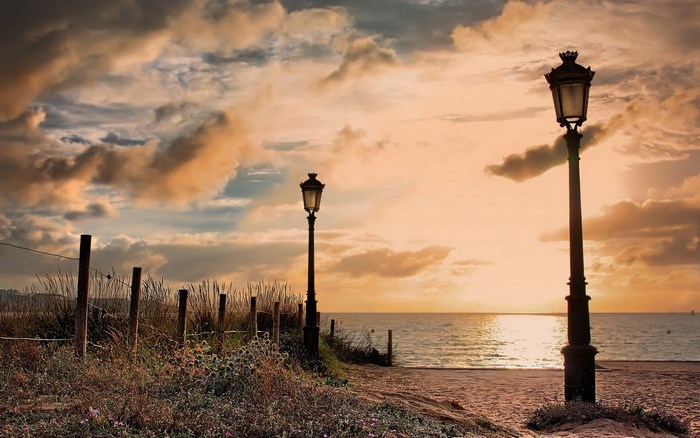 Two lamp posts on a beach at sunset