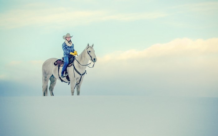 Cowgirl on a white horse in the snow