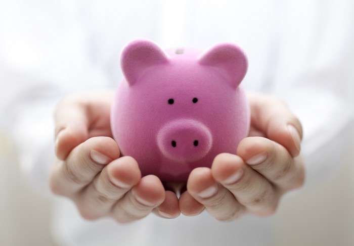 Pink piggy bank held in hands