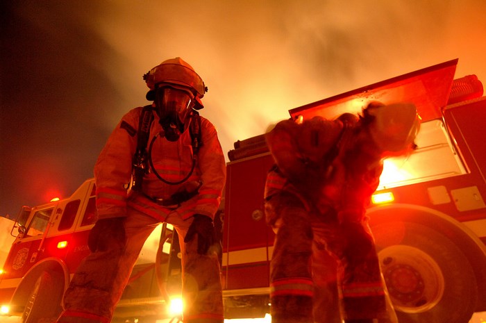 Firefighters in protective gear near a fire truck