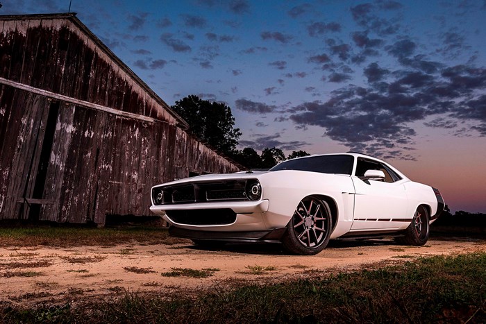 White Plymouth Barracuda parked by a barn at dusk