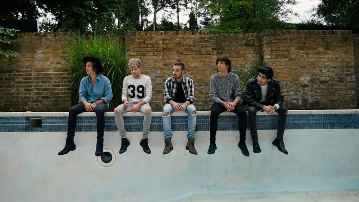 One Direction sitting by a pool