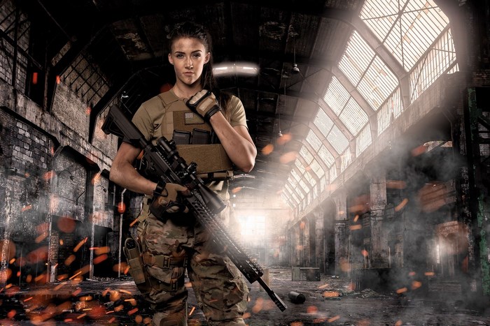 Woman in tactical gear holding a rifle in an abandoned building