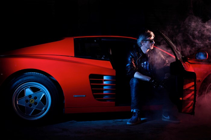 Man in leather jacket by red Ferrari Testarossa
